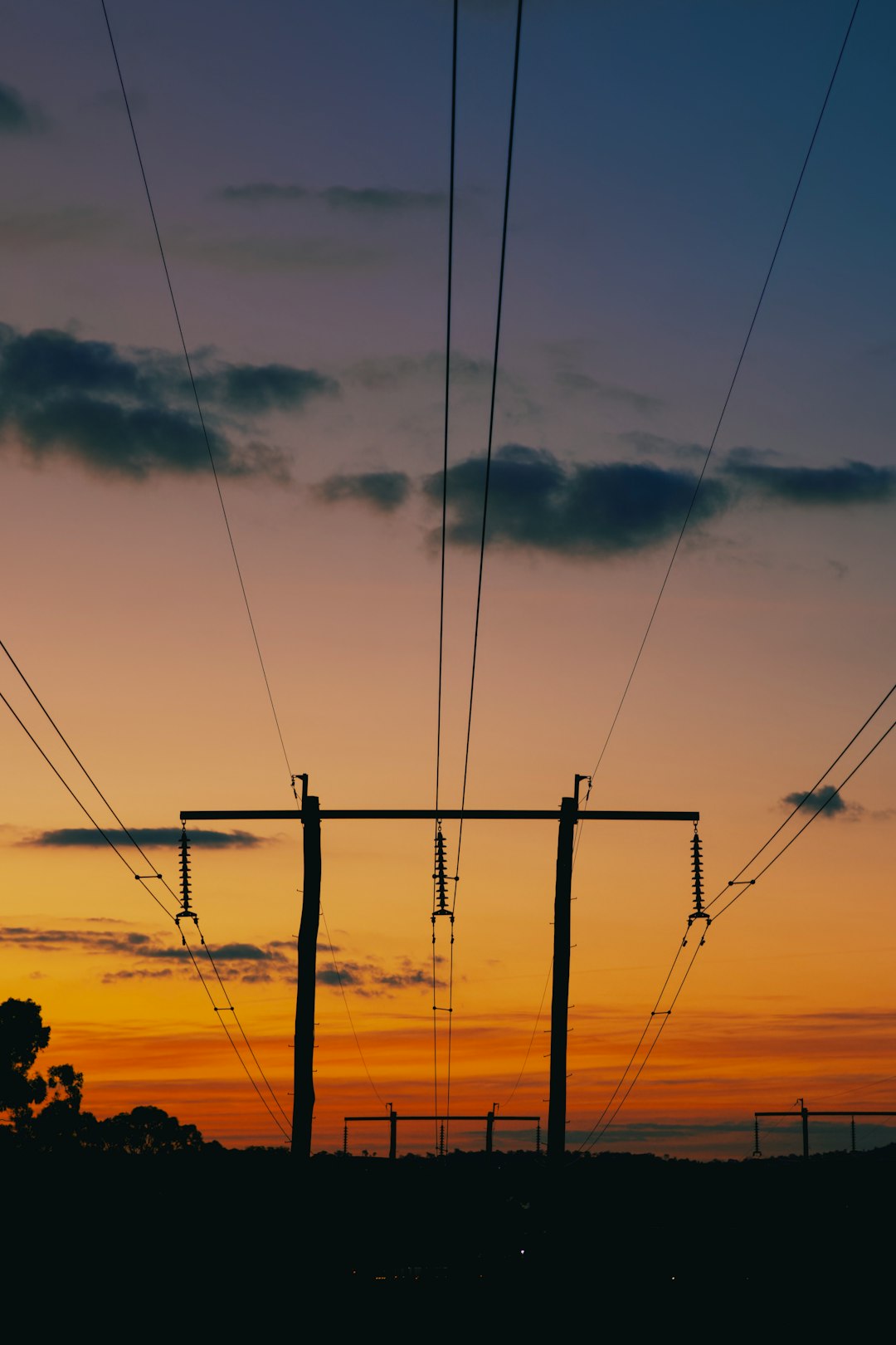 the sun is setting behind the power lines